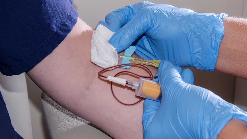 Nurse with gloves drawing blood from patient's arm